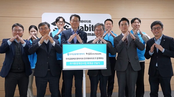 (왼쪽에서 다섯번째부터) 우리금융에프엔아이 김건호 대표이사와 이광회 사무총장이 지난 24일 한국해비타트 본사에서 열린 후원금 전달식에서 양사 임직원과 함께 기념촬영을 하고 있다(사진 = 우리금융그룹)