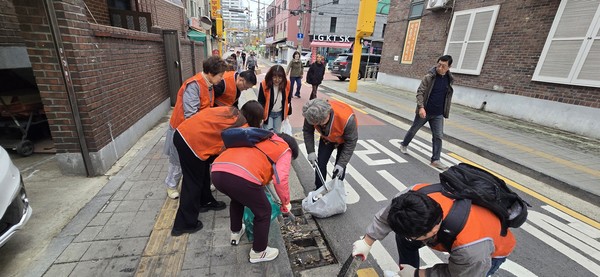 구로구소상공인연합회 회원들이 3월 31일 골목상권 일대에서 환경정화 봉사활동을 펼치며 빗물받이 내부까지 꼼꼼히 청소하고 있다(사진 = 구로구)
