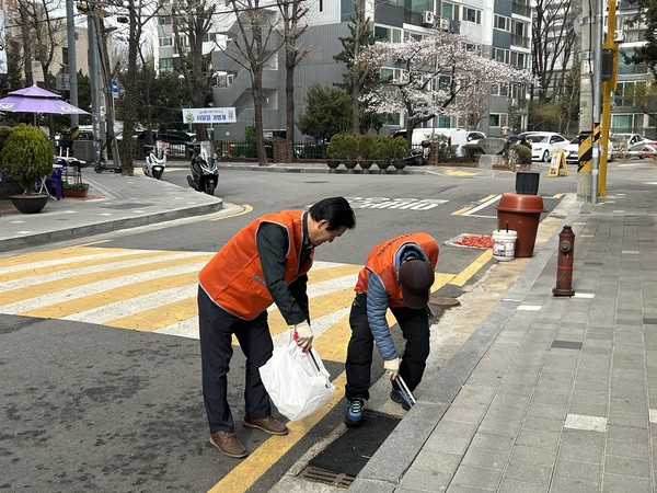 구로구소상공인연합회 회원들이 3월 31일 상권 일대에서 쓰레기 수거와 빗물받이 청소 등 환경정화 활동을 하고 있다(사진 = 구로구)